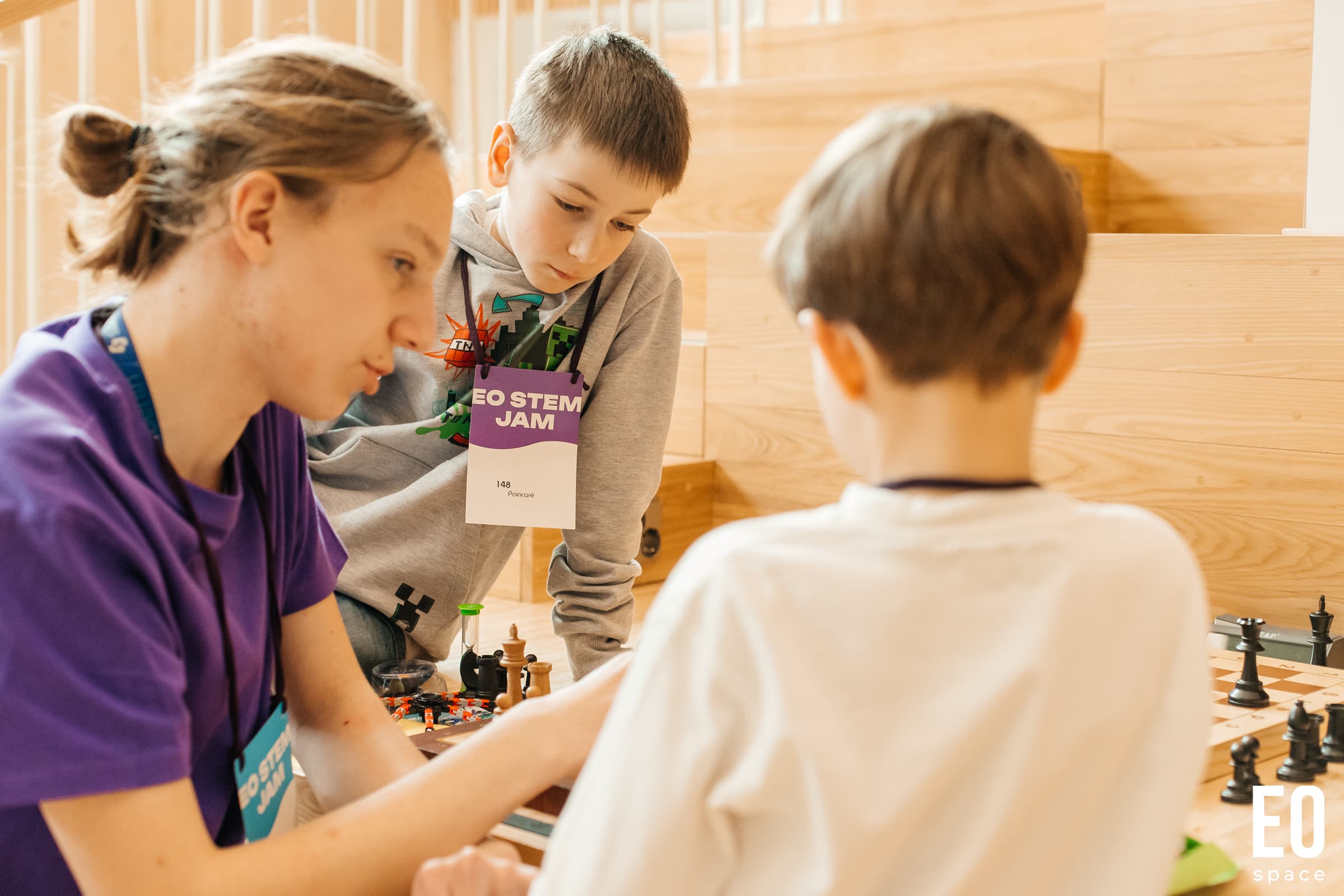 Vapaaehtoinen auttaa lapsia pulmatehtävässä EO STEM Jamissa